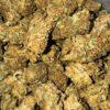 Close-up image of Grape Ape cannabis flower, a AA indica with purple-tinged buds and a THC range of 16%-19%.